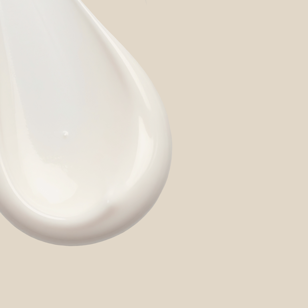 Close-up of a dollop of creamy white lotion or moisturizer on a light beige background.