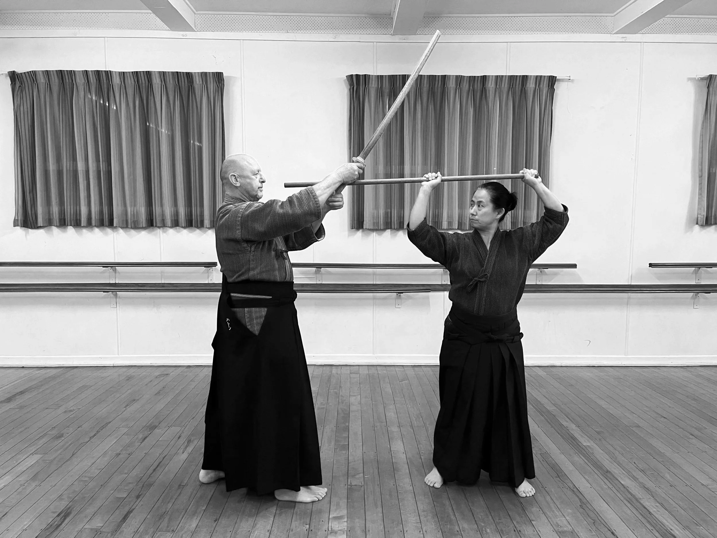 Two martial artists practicing  in a dojo. 