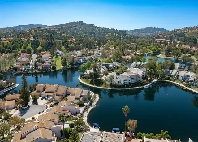 Aerial view of a Calabasas, CA with houses and a large lake surrounded by trees and hills.