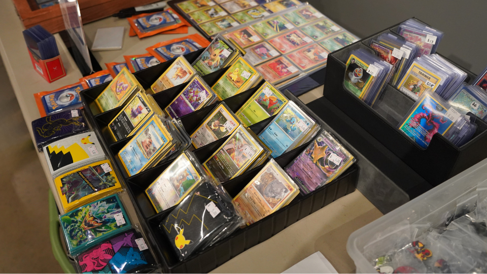 A table displaying a collection of Pokémon trading cards organized in black and transparent holders.