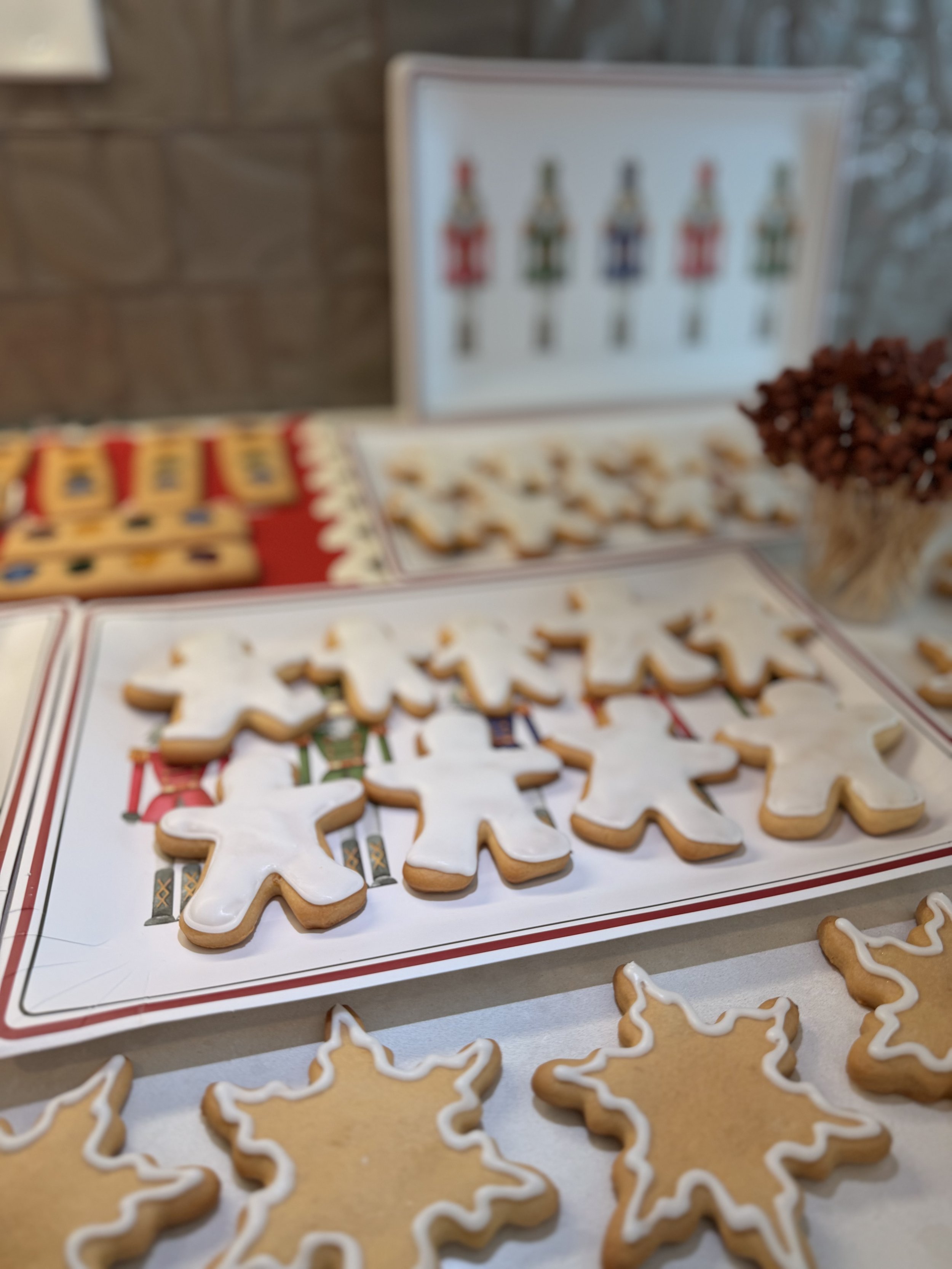 Christmas cookies decorated with white icing, arranged on holiday-themed trays.