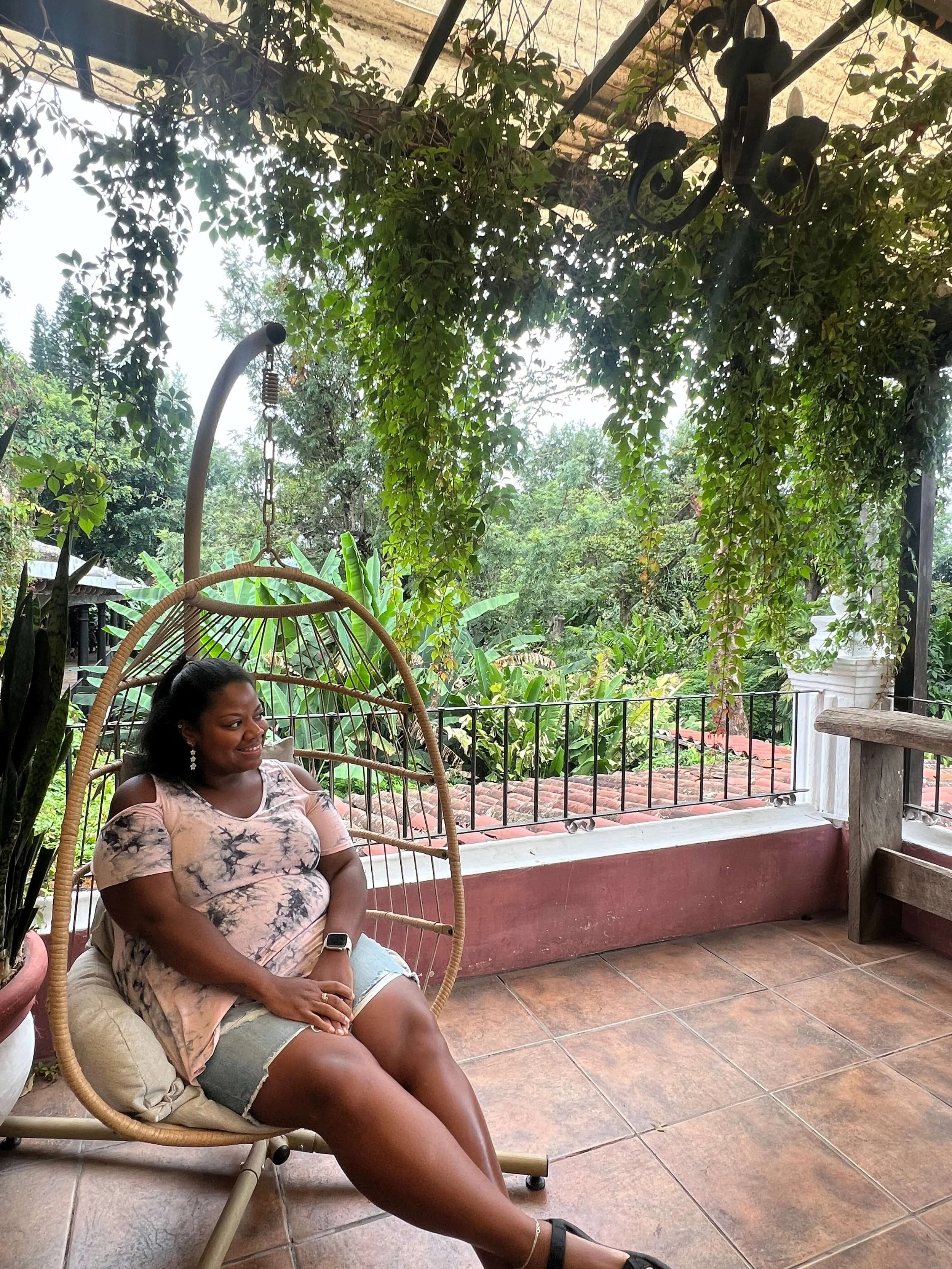 Lissette sitting in a wooden chair looking to the right in a forest