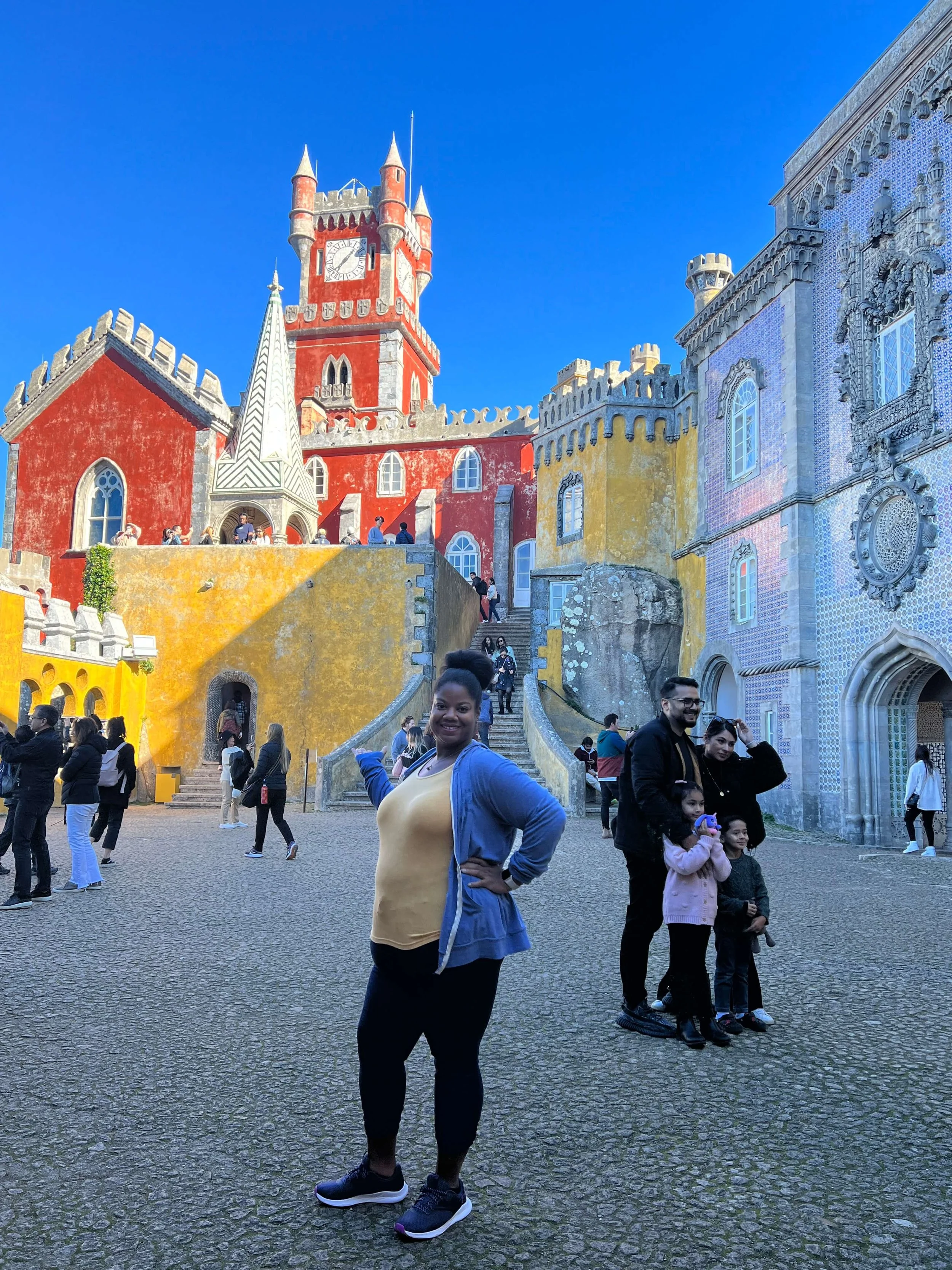 Lissette standing in front of Yellow, red and purple castles in Sintra, Portugal