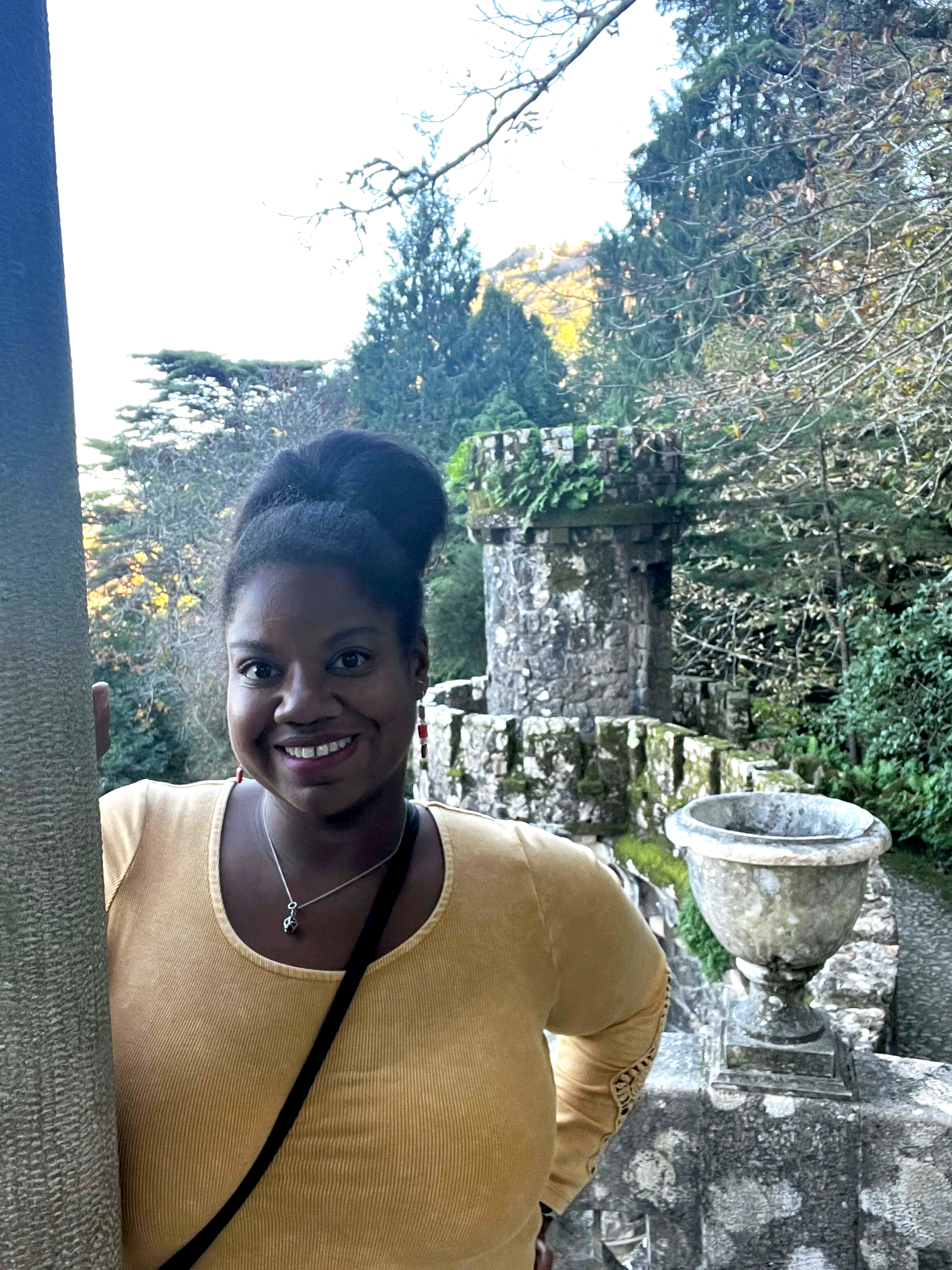 Close up of Lissette wearing a yellow shirt in front of a castle