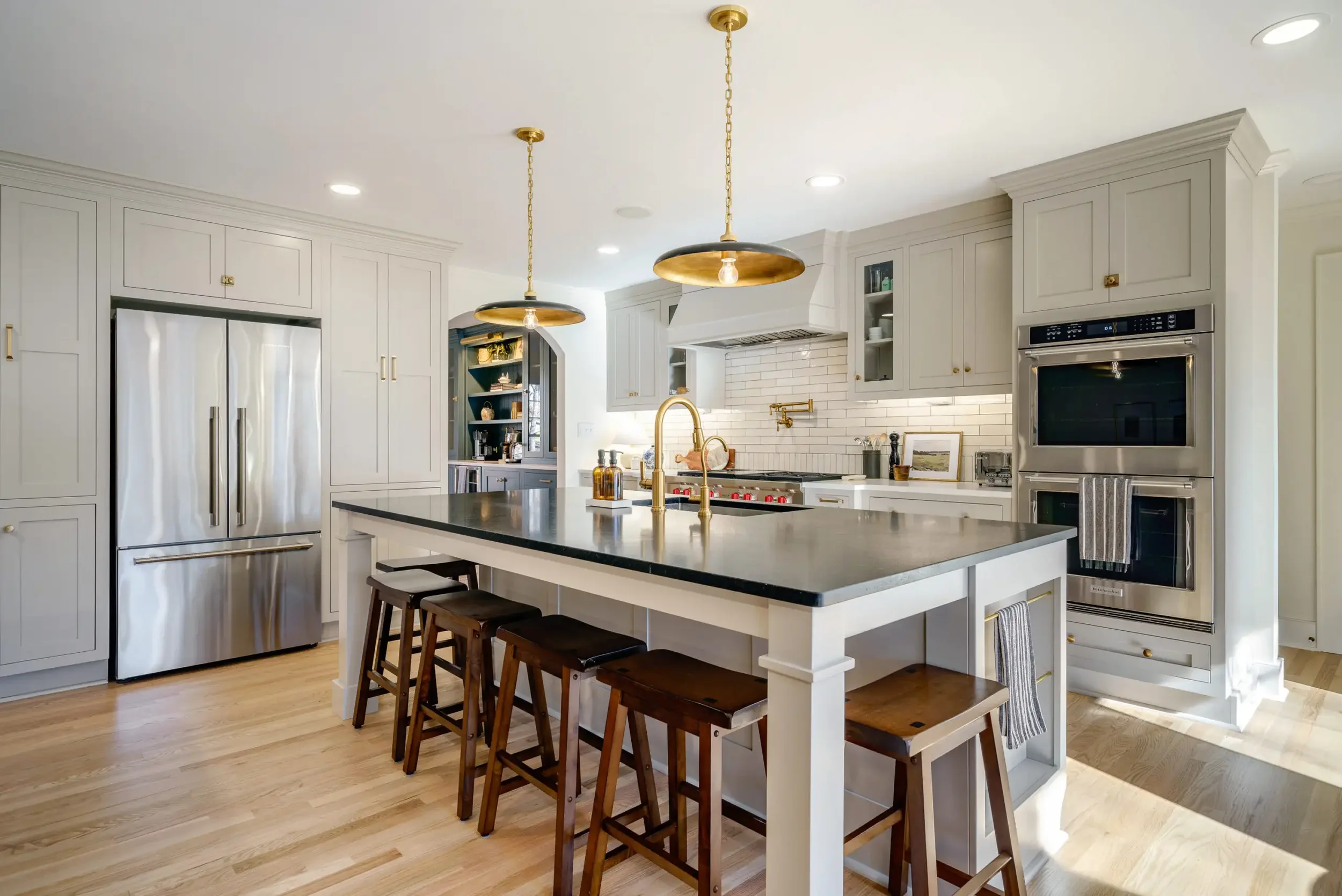 Modern kitchen with white cabinets, black countertop island, stainless steel appliances, and wooden bar stools.