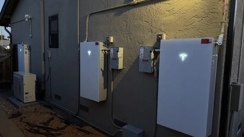 Electrical meters and boxes mounted on a beige exterior wall of a building with visible wiring and conduit.