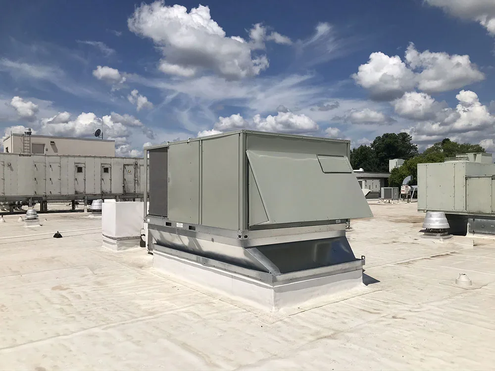 Rooftop HVAC units and vents under a partly cloudy sky.