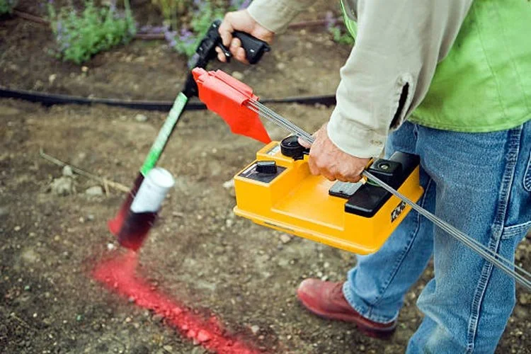 Person operating a soil sampling device outdoors in a garden or farm setting.