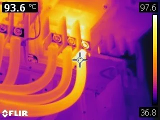 Thermal image of electrical components with warm cables and connections indicating heat presence.