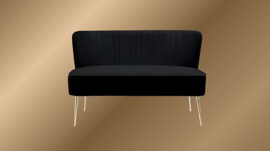 Black modern loveseat sofa with metal legs against a beige wall.
