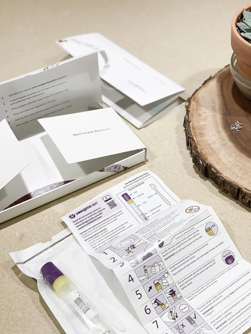 Open medical testing kit with instructions and supplies on a table, next to a wooden slab with a potted plant.