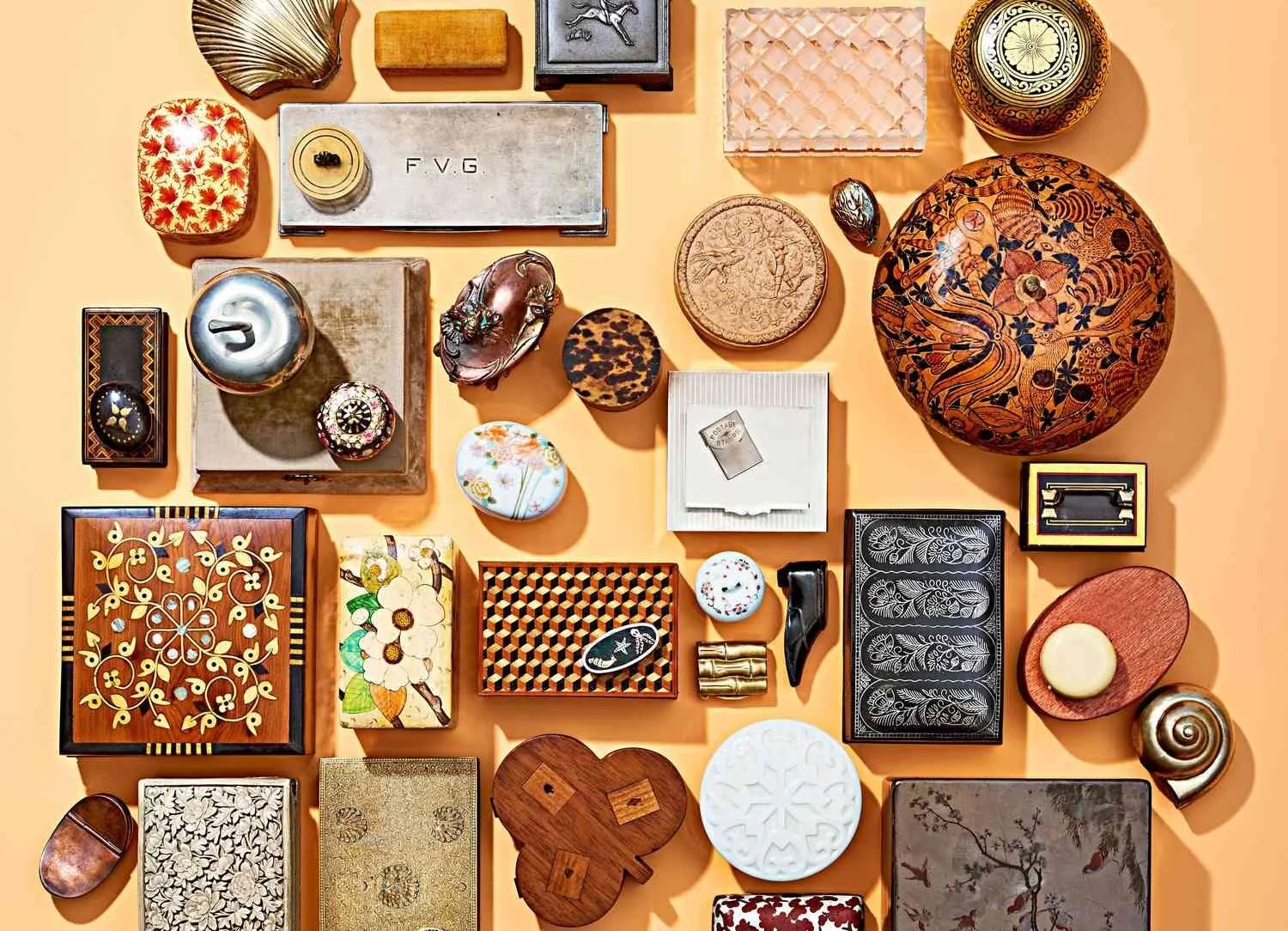 A collection of decorative items including boxes, bowls, a snail sculpture, a teapot, and various small decorative objects arranged on a peach-colored surface.