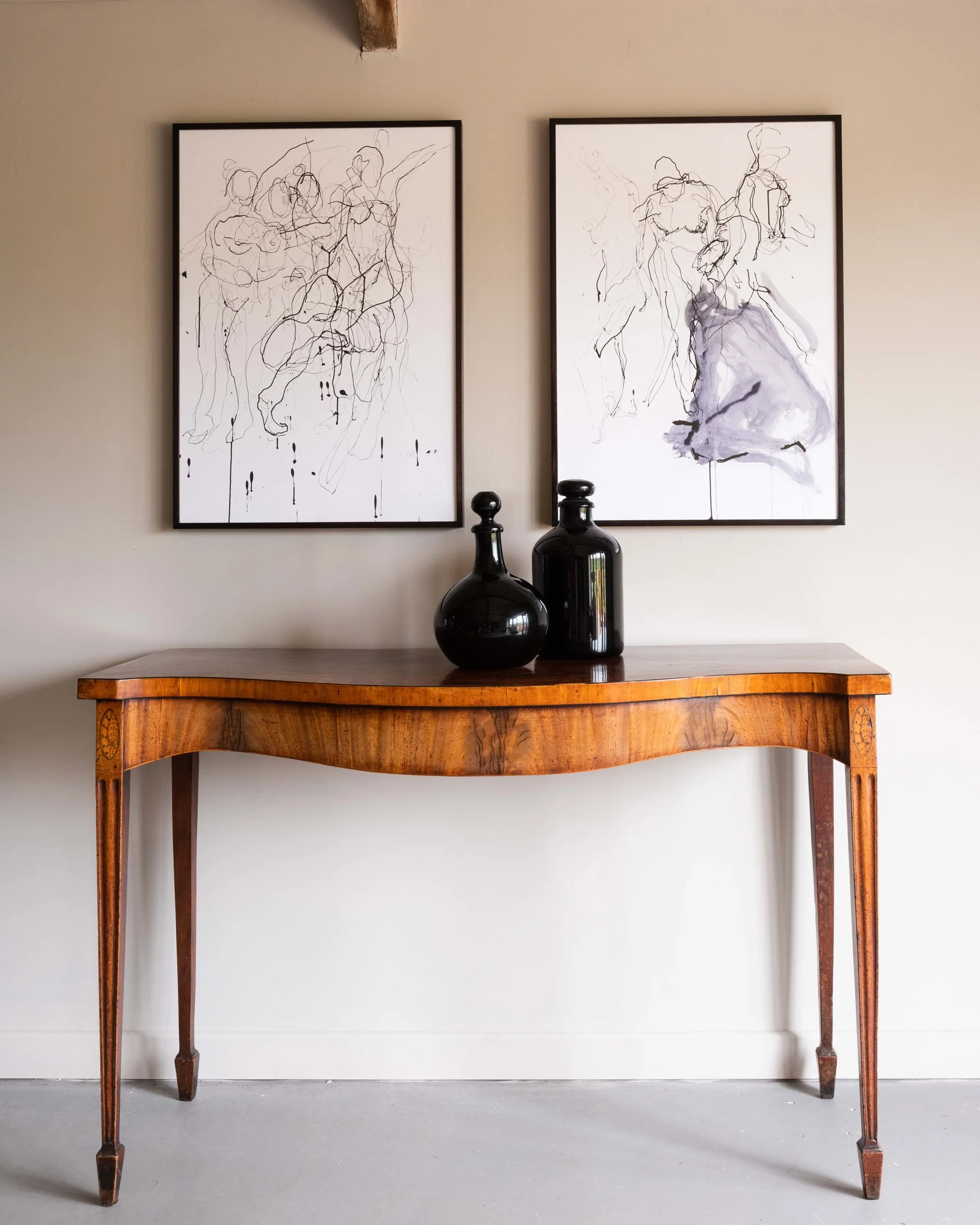 Drawings by Charlotte Hickman hanging alongside an antique side table
