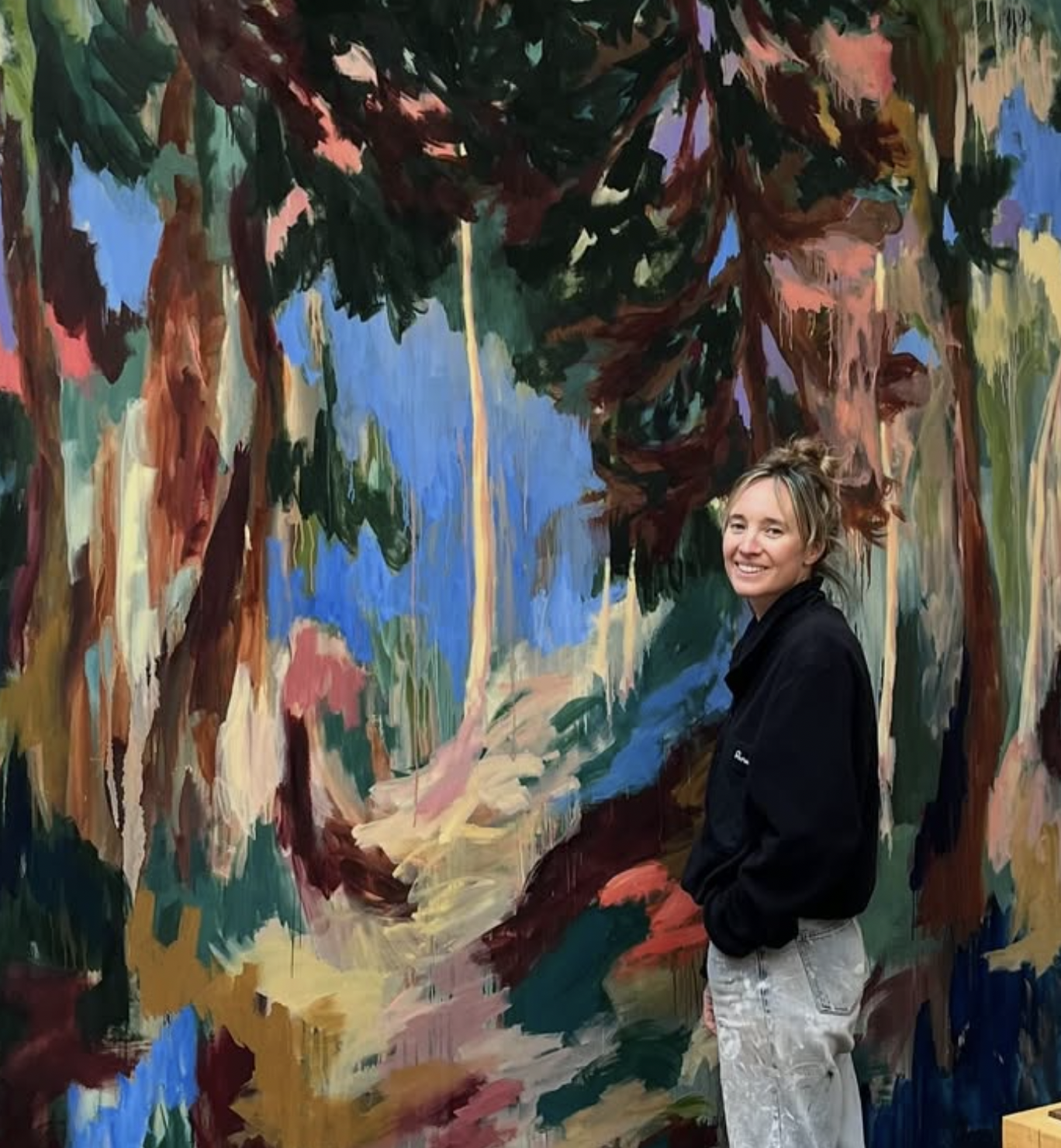 Portrait of artist Mary West next to one of her large scale paintings