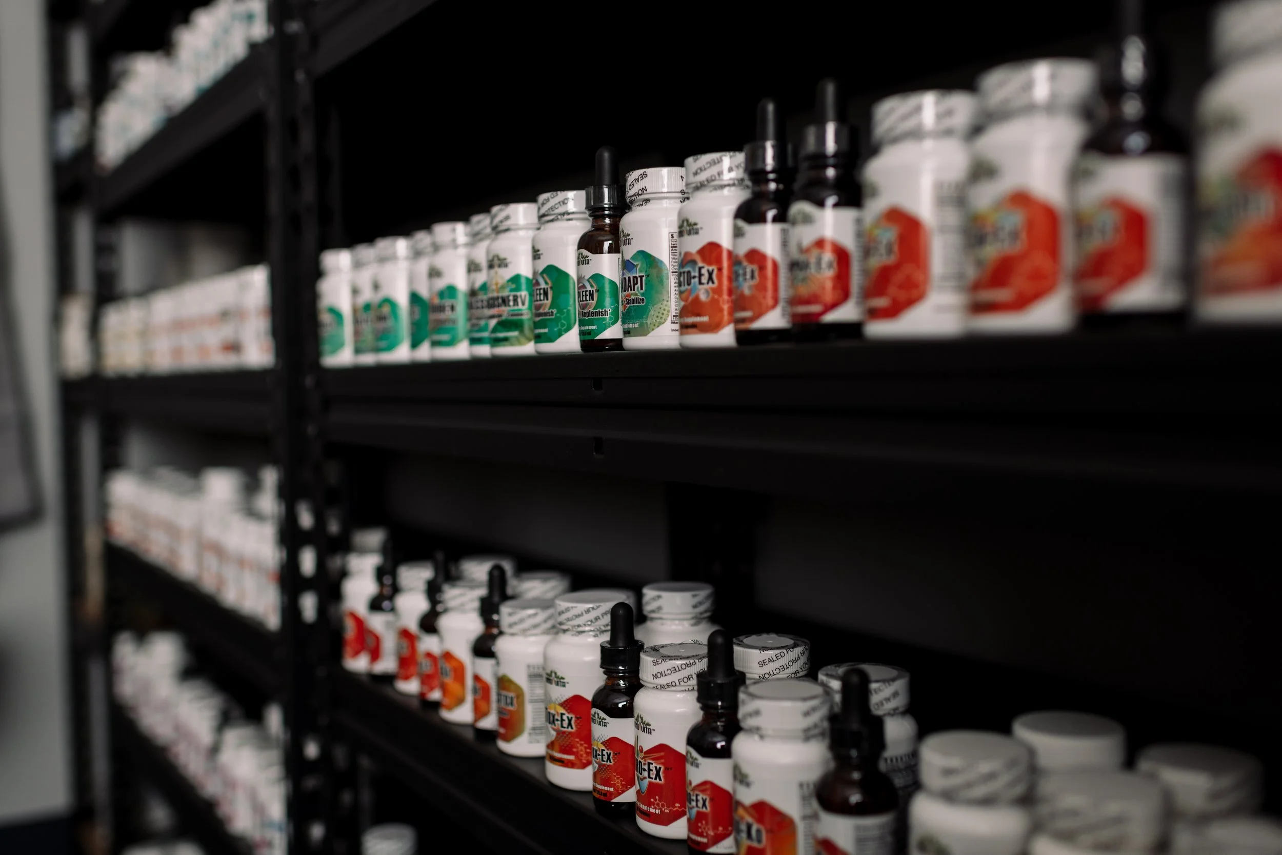Shelf with various bottles and jars of dietary supplements or vitamins, some with droppers.