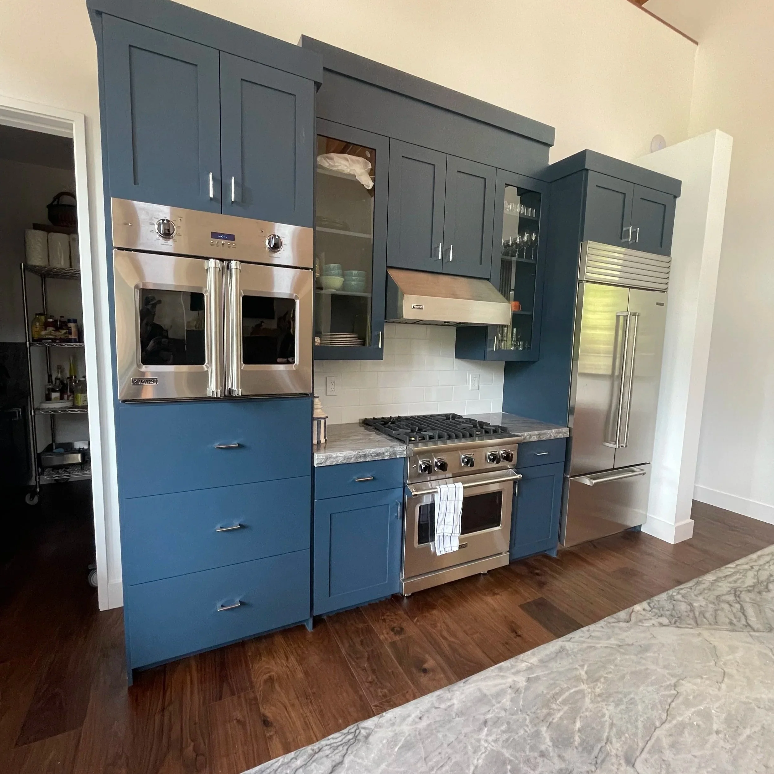 Custom kitchen remodel in Reno, NV featuring modern blue cabinetry, marble countertops, and a professional white brick tile backsplash installation by Revive Tile Co.
