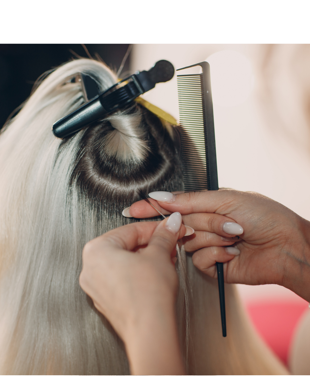 Close-up of a hairstylist using a needle and thread to sew a hair extension onto a client's scalp, with a black comb and a hair clip holding the client's long, blond hair.
