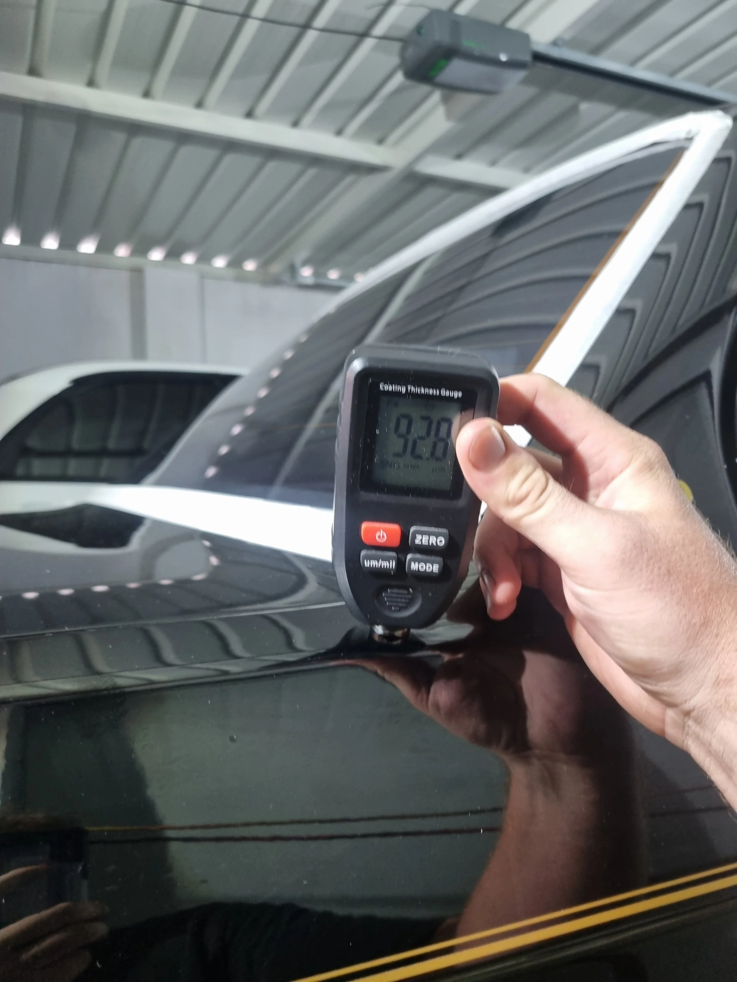 Professional paint thickness measurement in Perth. A paint depth gauge test on a rare black BMW E30 323i JPS Edition, essential for clear coat safety before detailing.