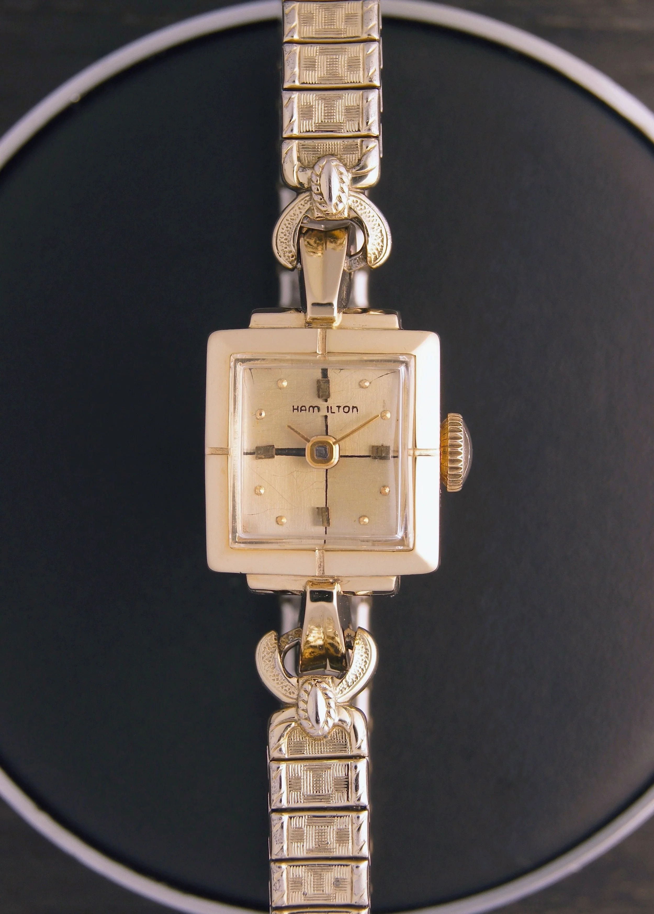 Vintage Hamilton wristwatch with a square gold-tone face and metal strap.