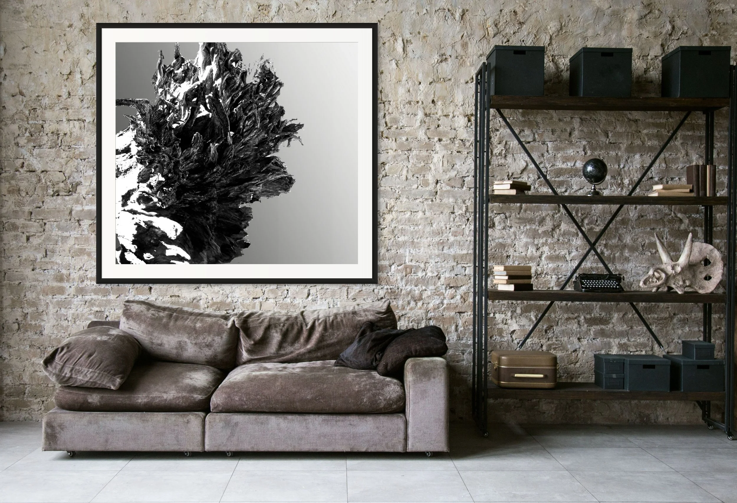 Modern living room with a beige velvet sofa, black and white abstract art on a brick wall, and a black metal bookshelf with decorative items and books.