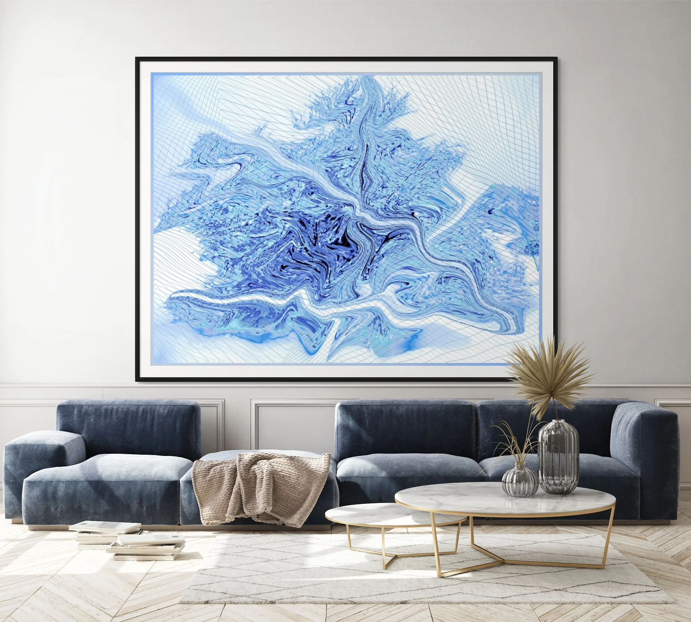 Modern living room with a dark blue velvet sofa, beige blanket, and a white round coffee table with a gold frame. Behind the sofa is a framed blue and white abstract artwork on the wall. To the right are decorative vases and tall dried plants. The fl