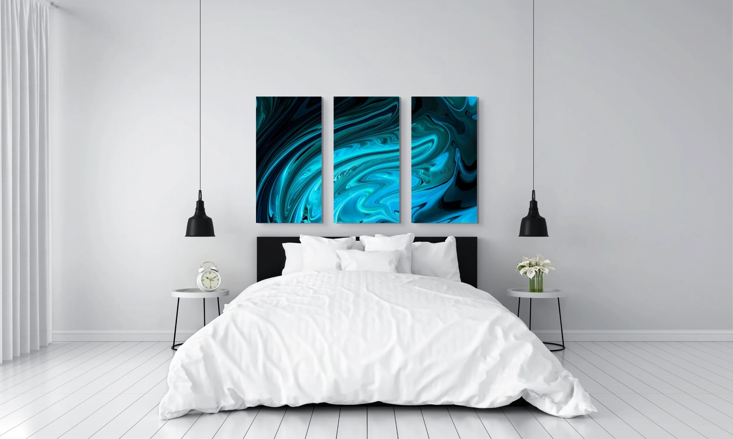A modern bedroom with a white bed, black headboard, white bedding, and two small white side tables with black legs. One side table has an analog alarm clock, and the other has a vase with white flowers. Above the bed are three large abstract blue and black paintings, and two black pendant lights hang on either side of the artwork. To the left are white curtains.