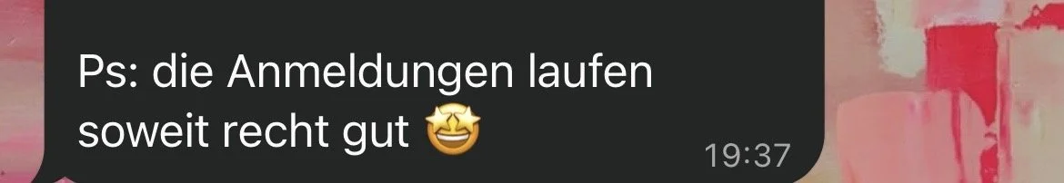 Screenshot eines Chat-Nachrichtentextes. Der Text lautet: "Ps: die Anmeldungen laufen soweit recht gut" mit einem lachenden Emoji. Im Hintergrund ist eine farbenfrohe Wand mit Pink- und Rottönen.