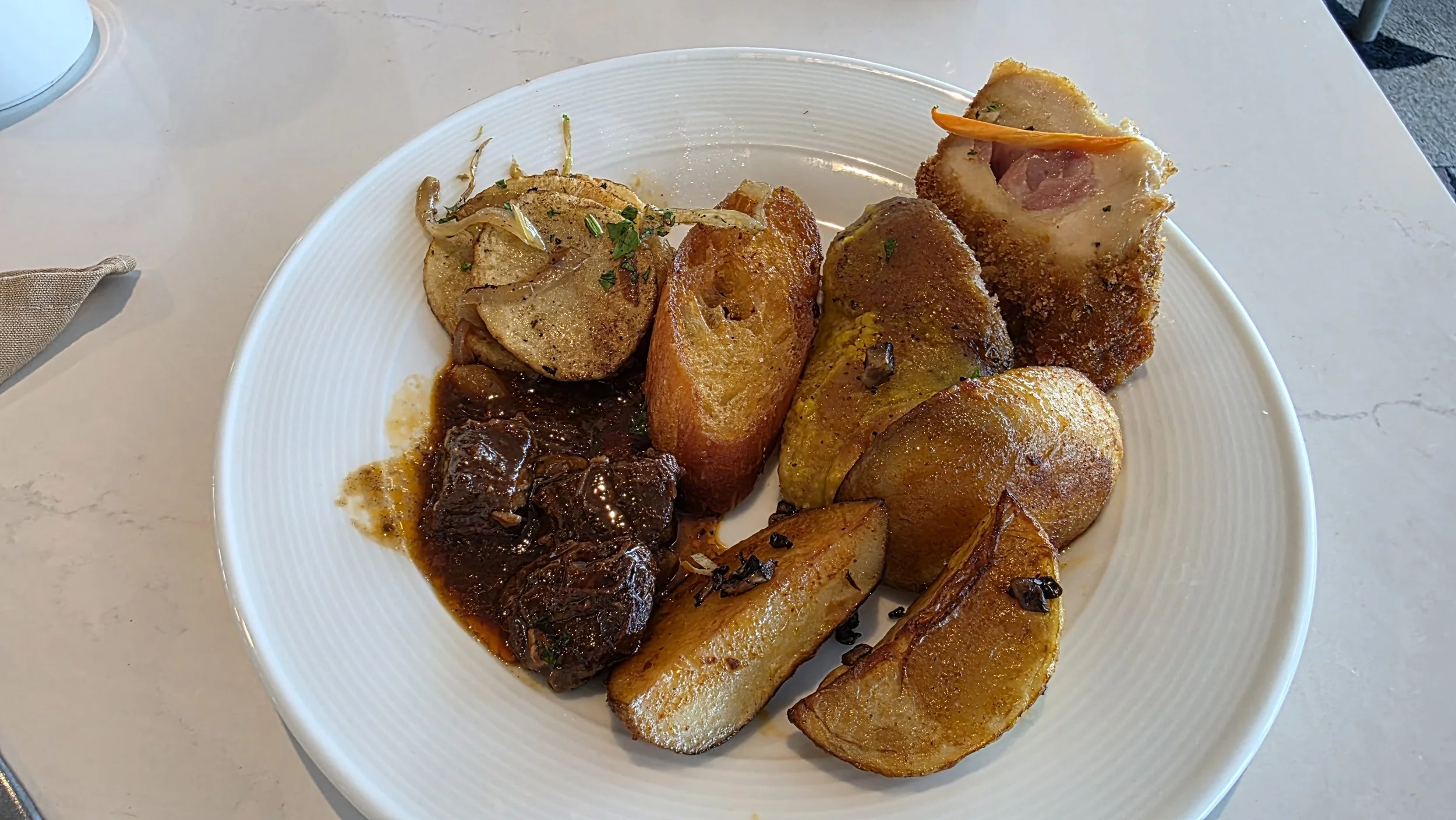 Plate of assorted roasted meats, potatoes, and vegetables served on a white dish.