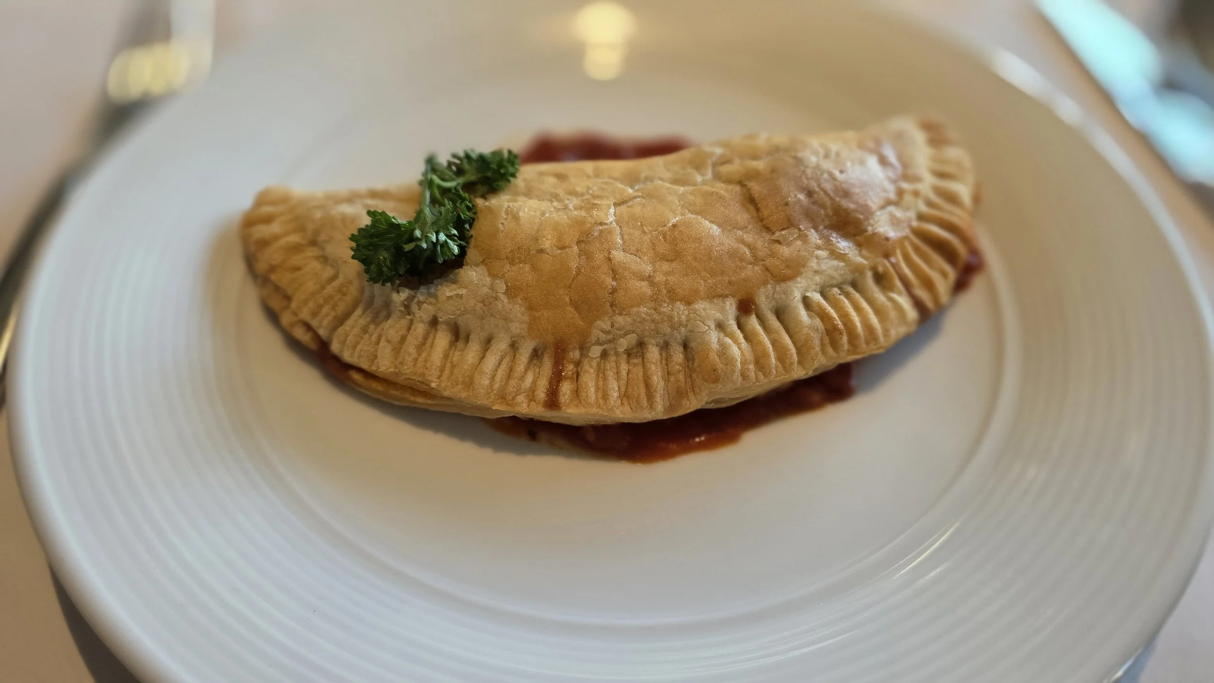 Fried calzone on a white plate with a garnish of parsley.