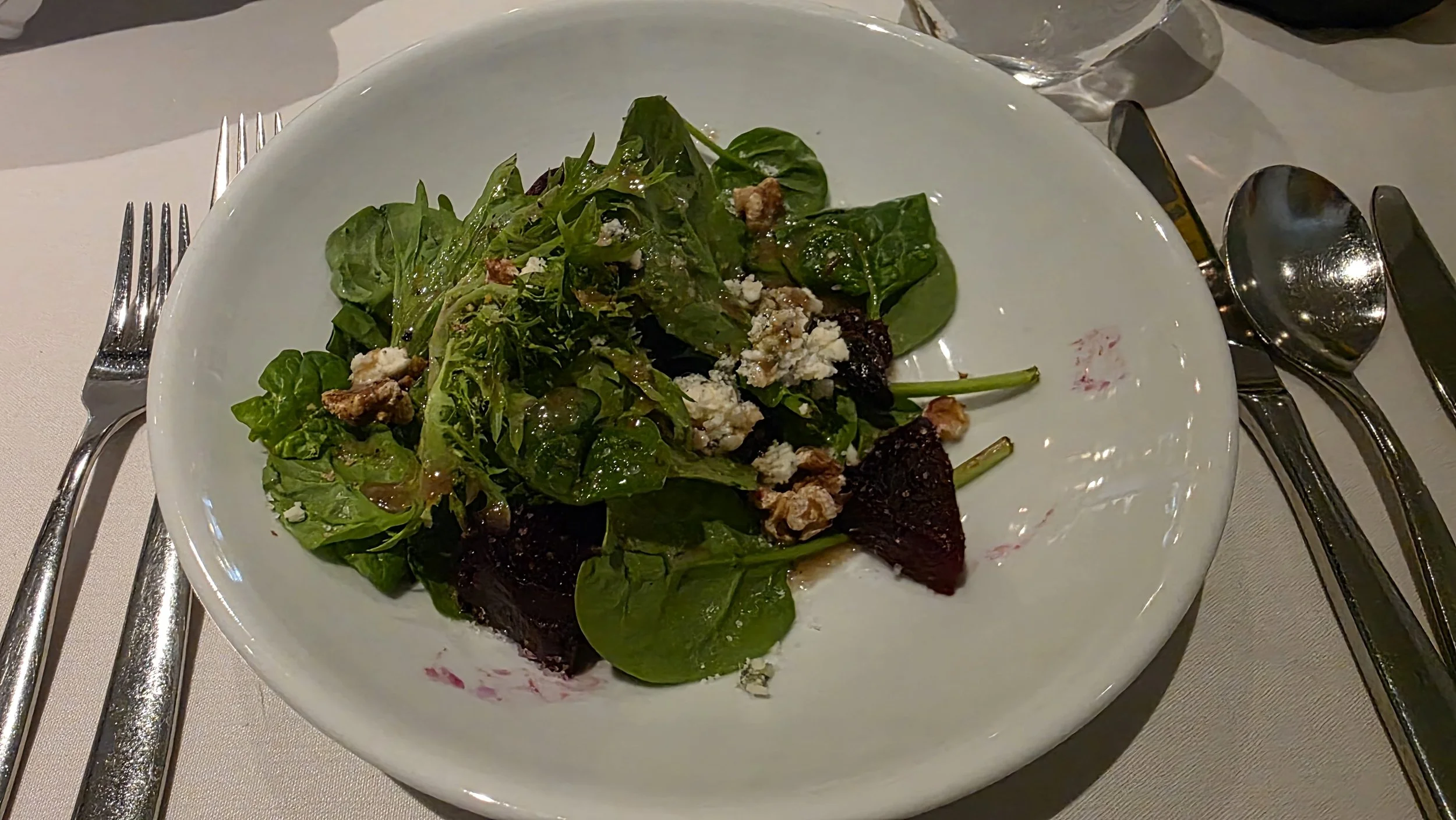 Fresh green salad with crumbled cheese and nuts on a white plate