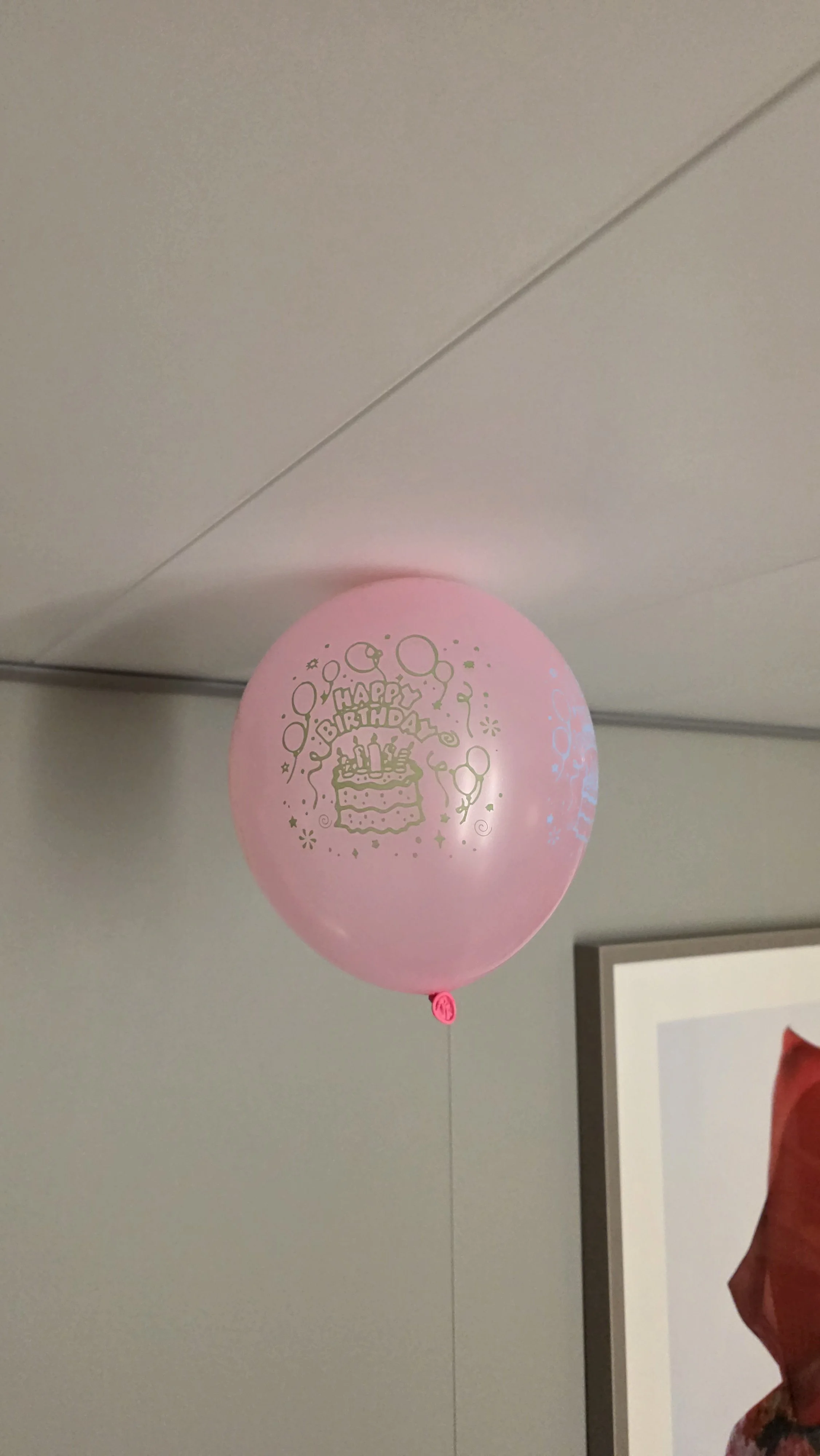 Pink birthday balloon with gold 'Happy Birthday' text, a birthday cake illustration, candles, balloons, stars, and confetti design.