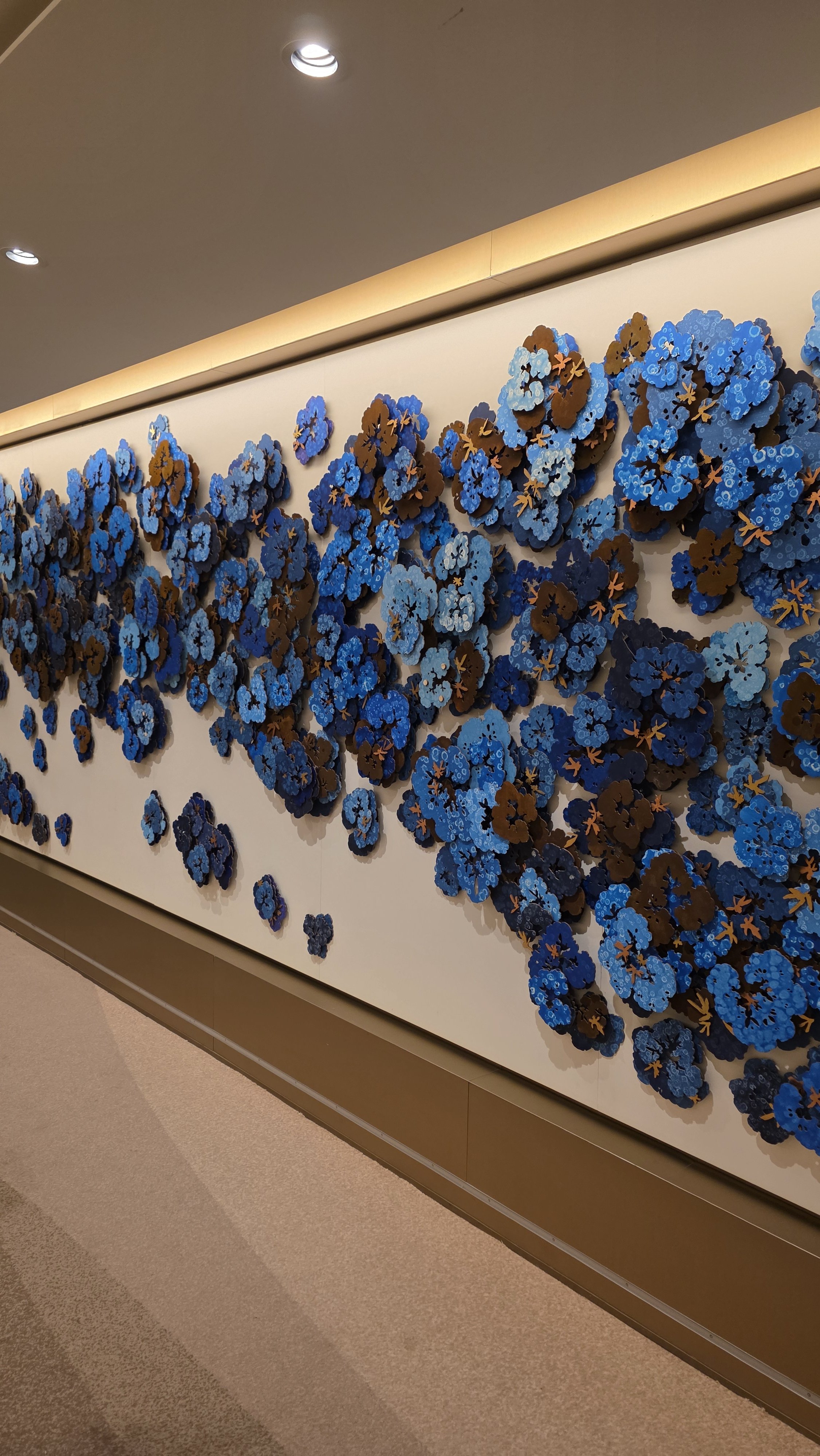 Decorative wall art featuring three-dimensional blue and brown floral designs arranged in an abstract pattern.