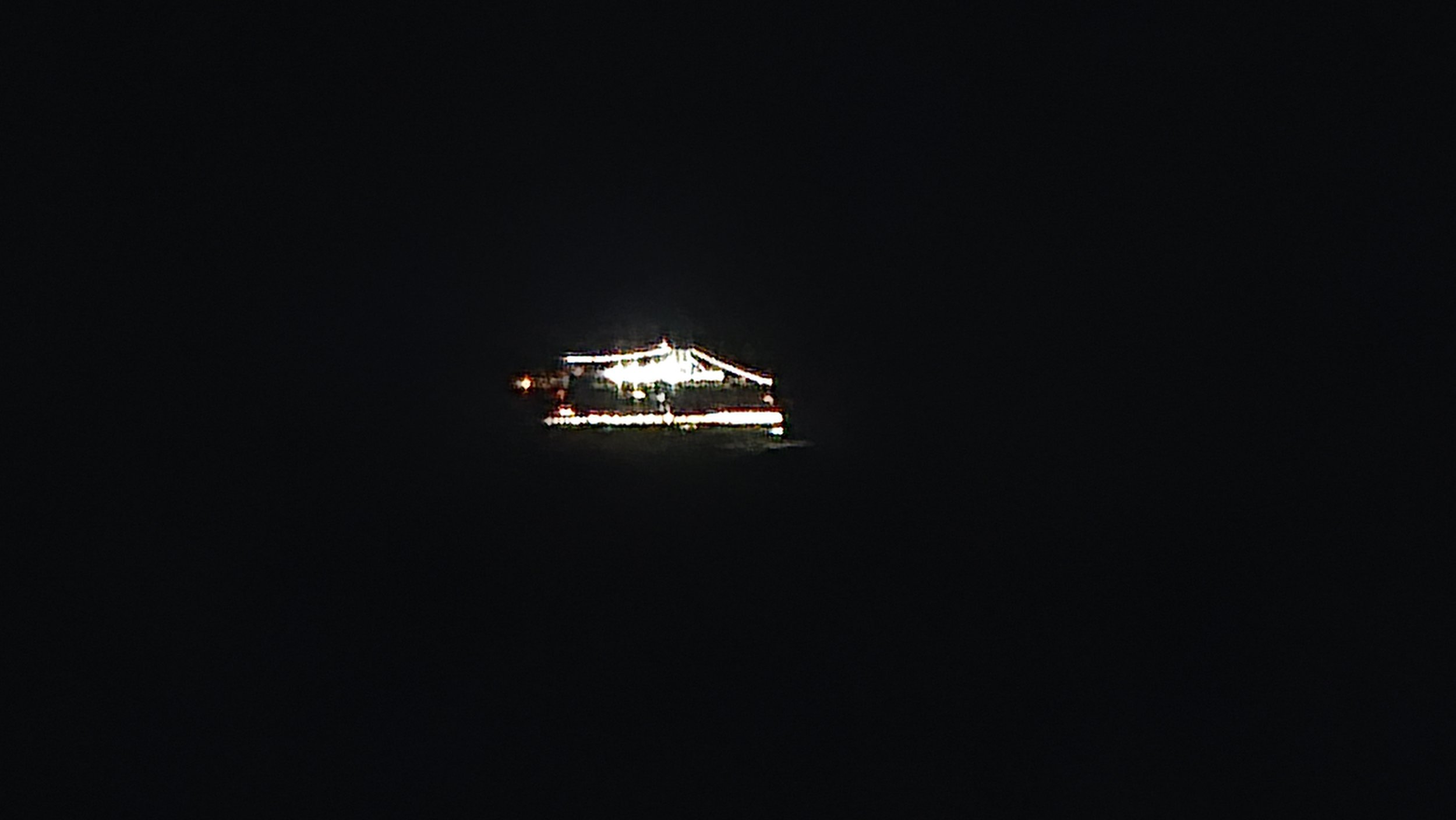A helicopter with illuminated lights flying in a dark night sky.