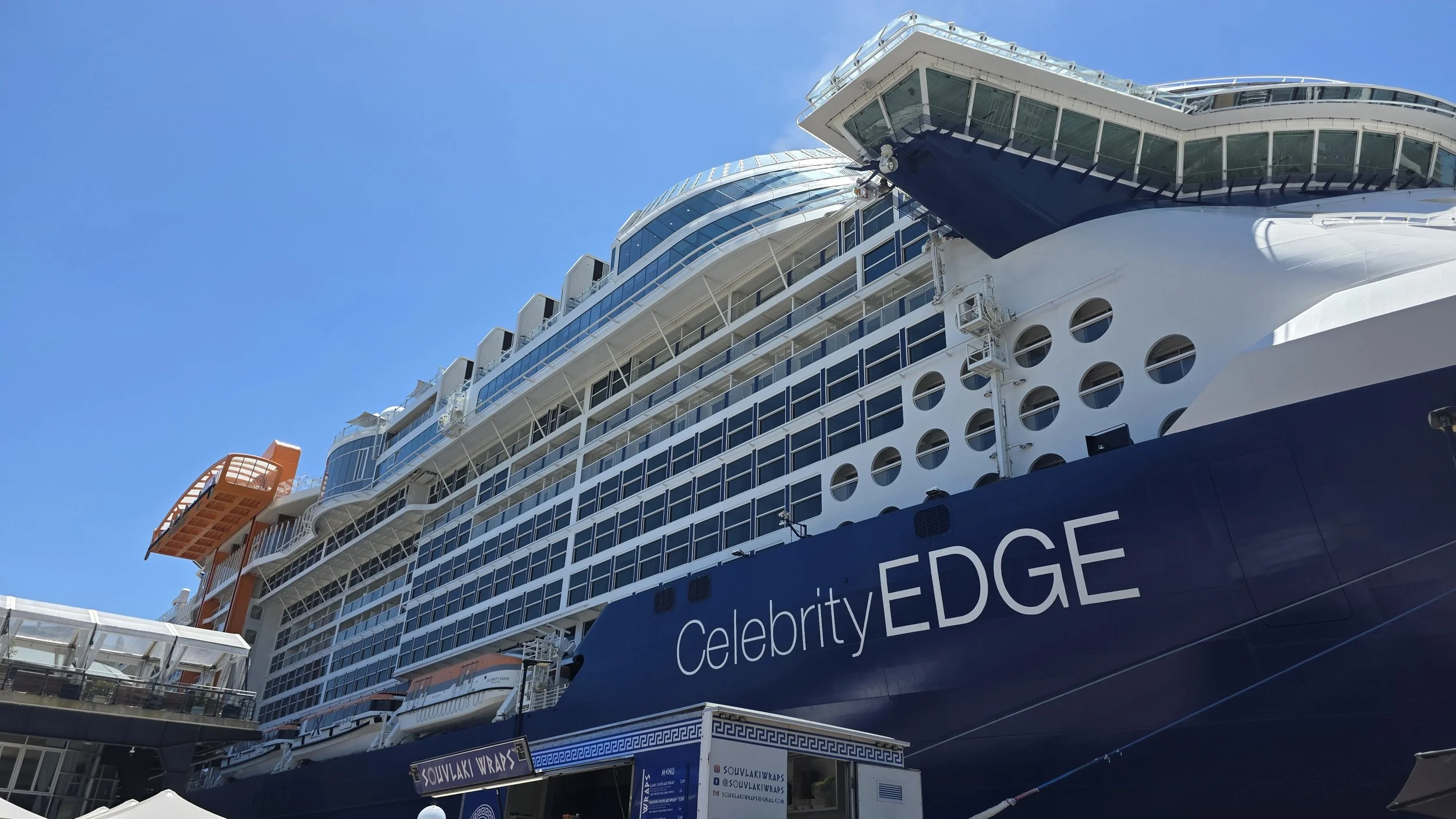 Cruise ship named Celebrity EDGE docked at port under a clear blue sky.