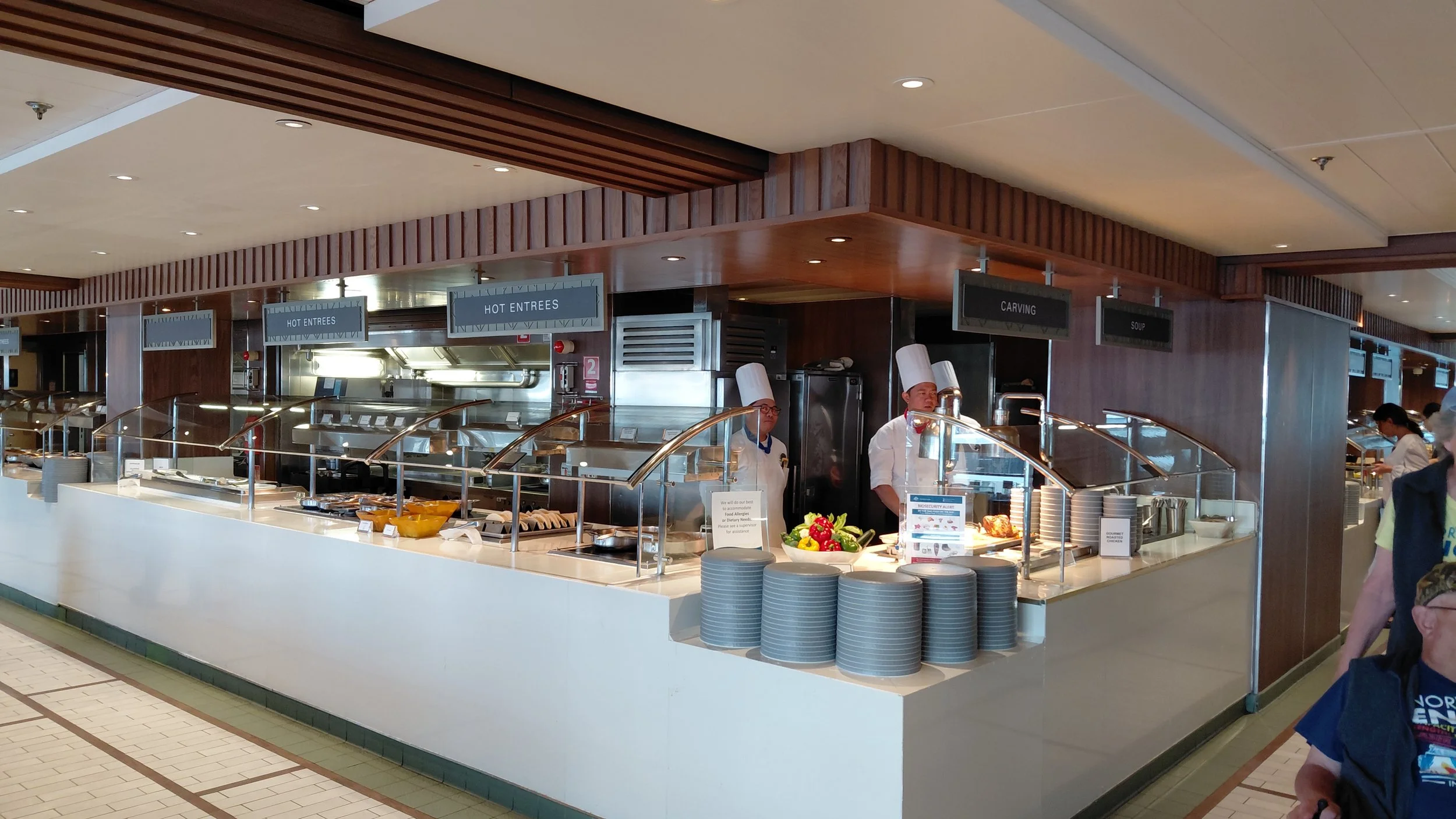 Buffet station with chefs preparing hot entrees, carving station, and soup station in a restaurant or cafeteria setting.