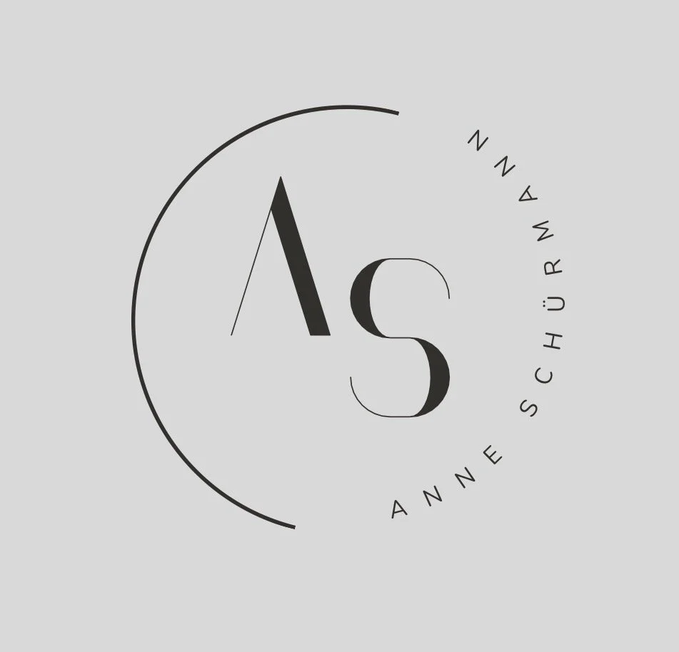 A modern logo with the letters 'A' and 'S' in the center, surrounded by a curved line and the words 'Anne Schürmann' arranged in a semi-circle.