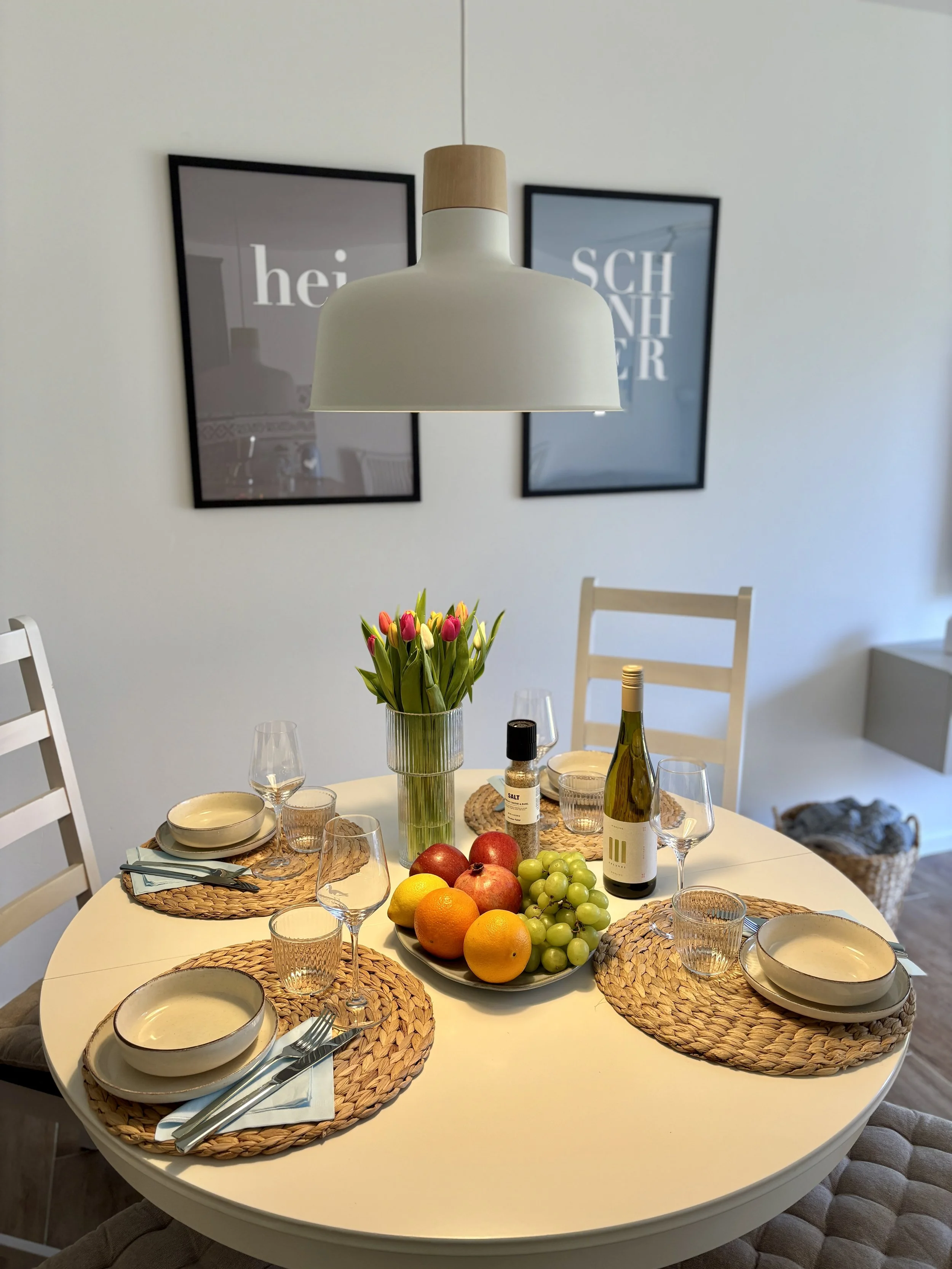 Ein gedeckter Esstisch mit Obst, Blumen und Geschirr in einem Esszimmer.