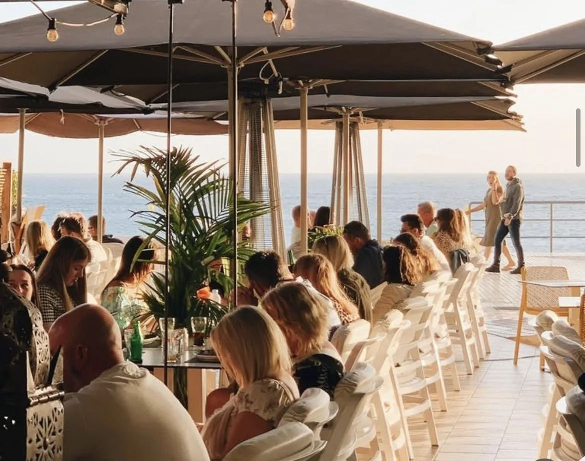 Guests enjoying sunset drinks on the terrace of Mokelino by the sea in Los Cristianos.