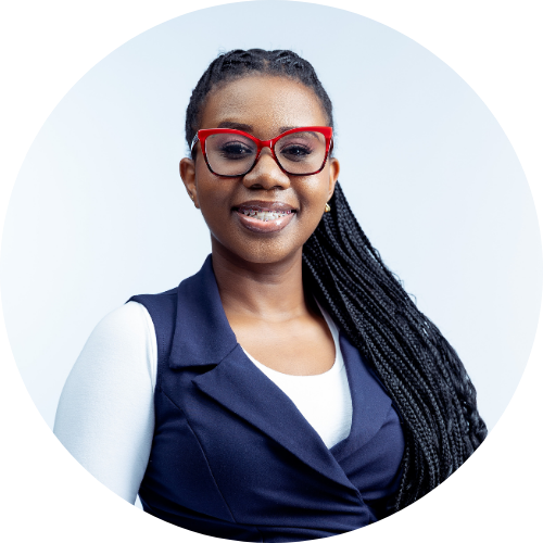 A woman with glasses and long braided hair, smiling and wearing a navy blue vest over a white shirt.