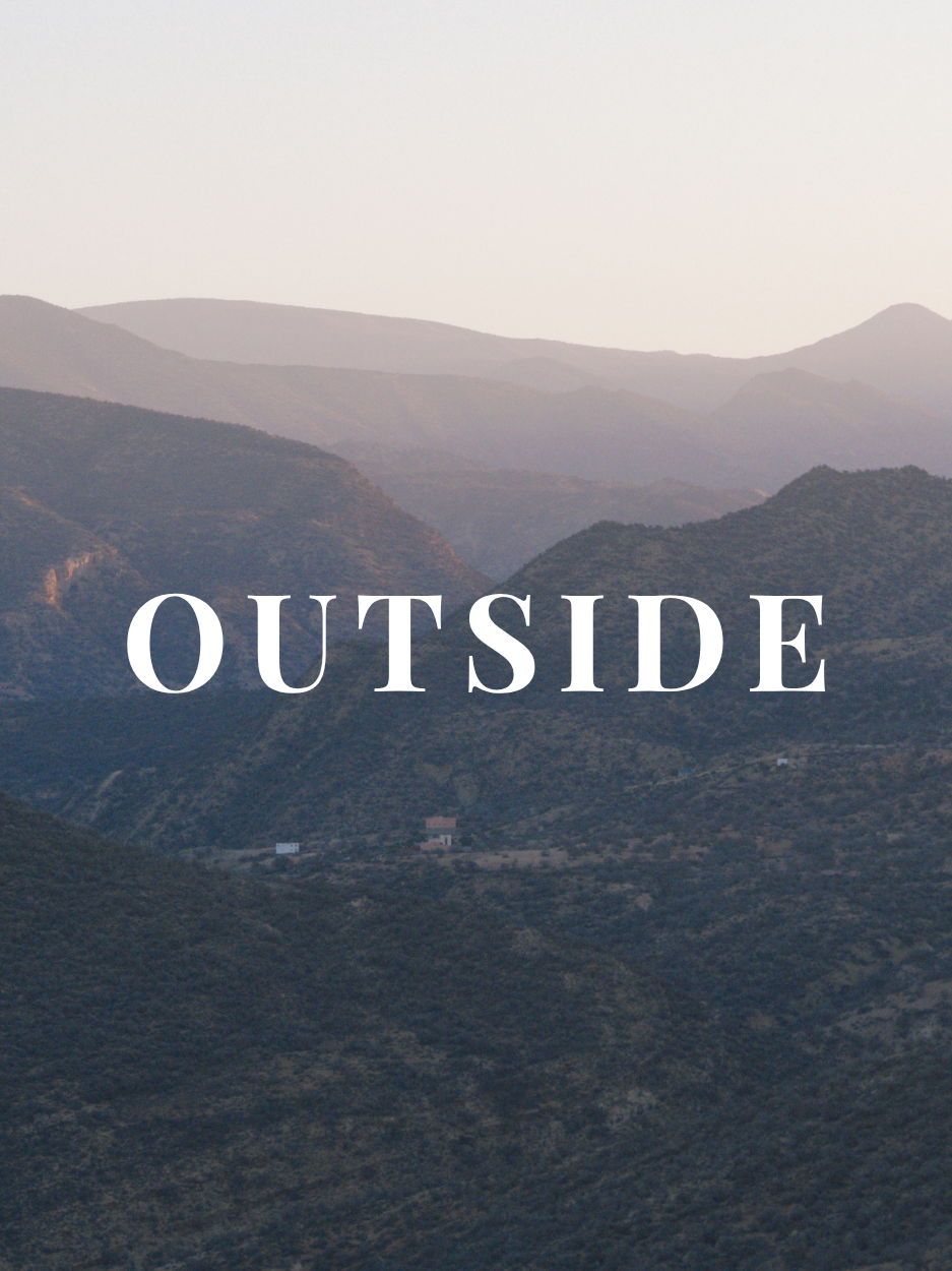 Landscape of mountains with the word 'OUTSIDE' written across in white text.