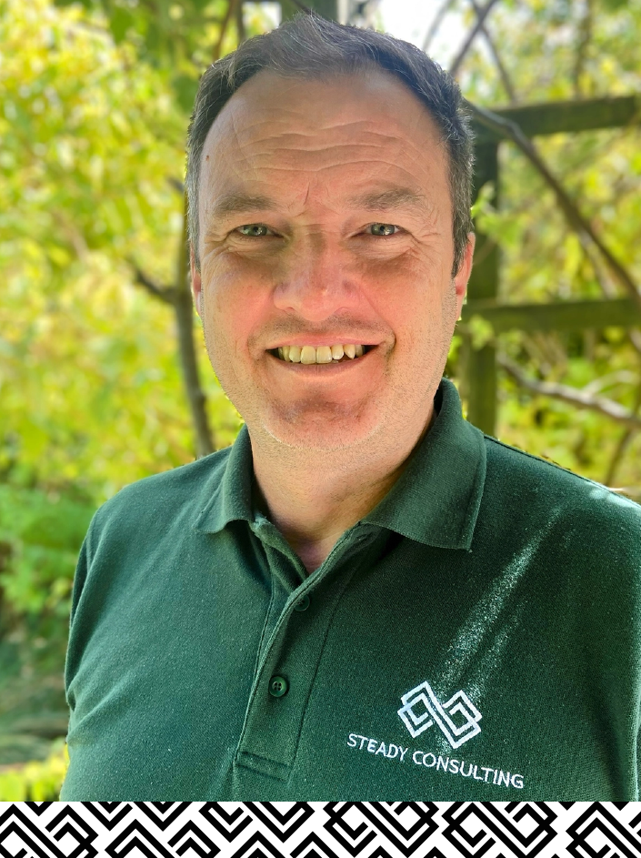 Neil Stead, small business consultant UK at Steady Consulting in the UK smiling at the camera wearing a green Steady Consulting polo next shirt