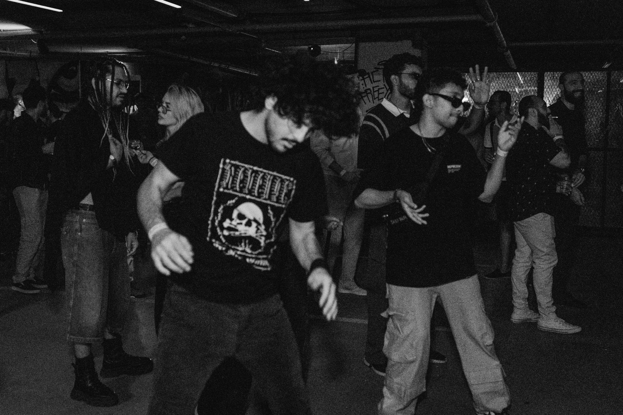 Group of young people dancing and enjoying music at a crowded indoor party or club, in black and white.