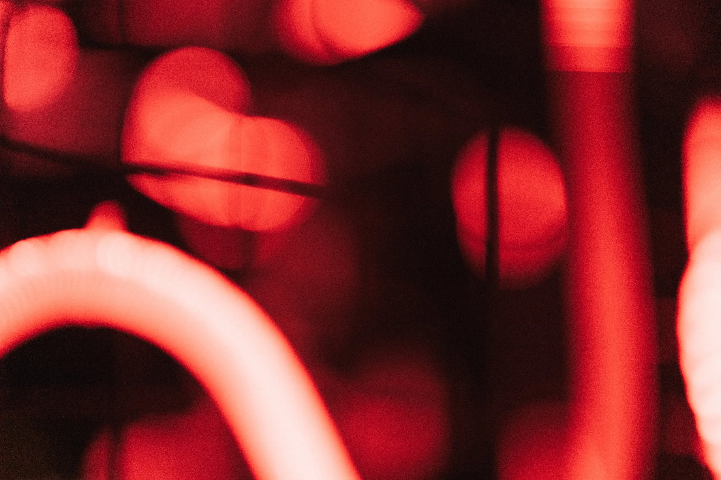 Close-up of blurred red and pink circles of light with some dark areas.