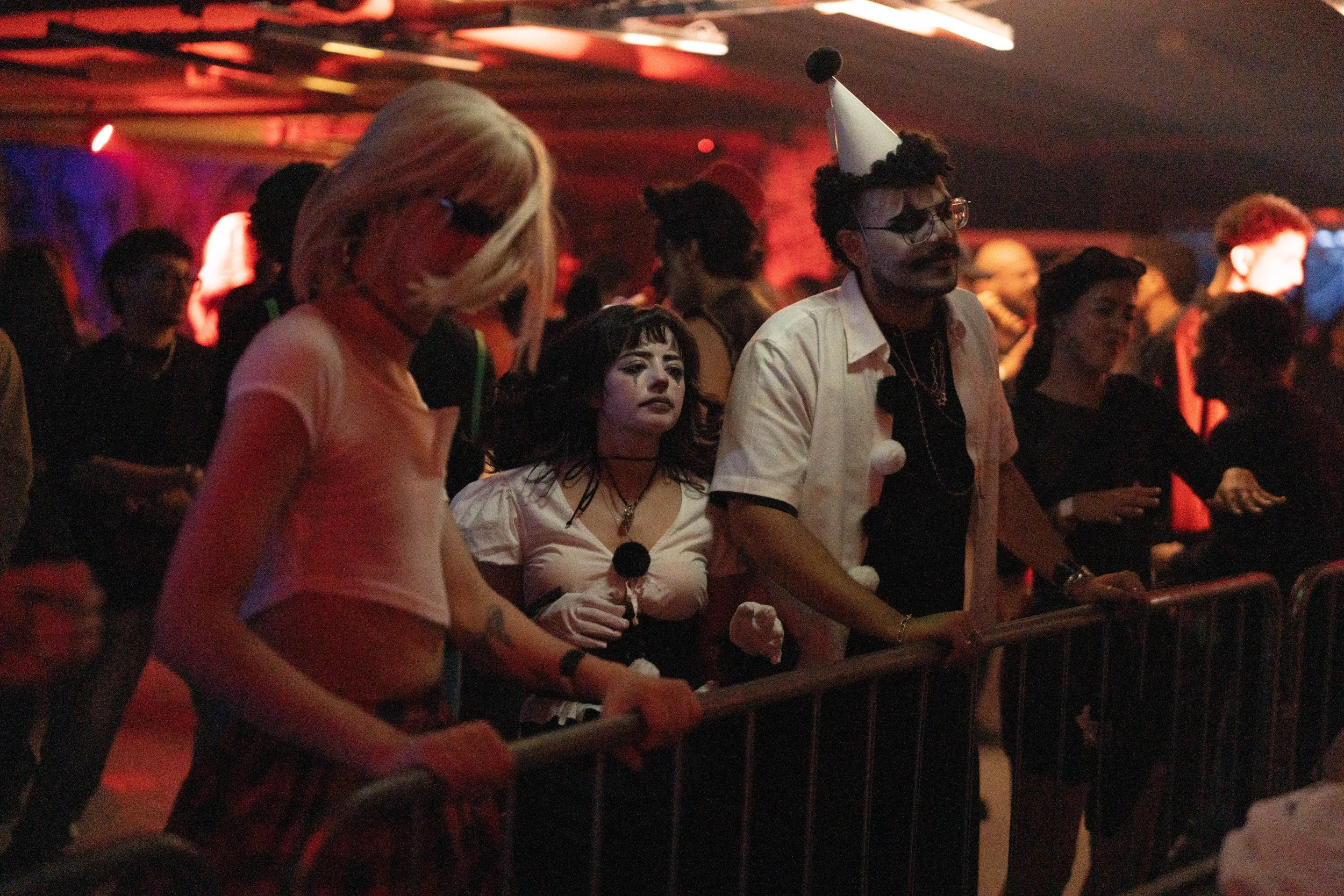 People dressed in costumes attending a party or concert with a venue filled with colorful lights.