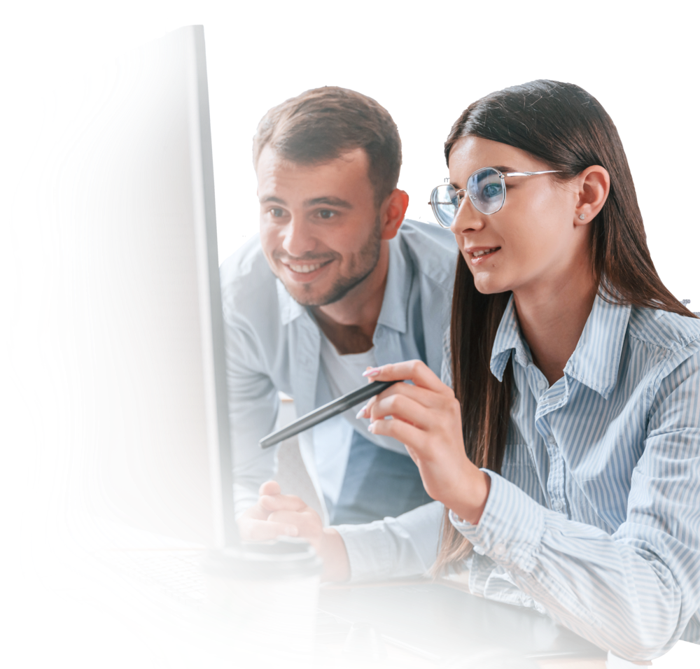 Two people collaborating at a computer, woman pointing at screen with stylus, coffee cup on desk.