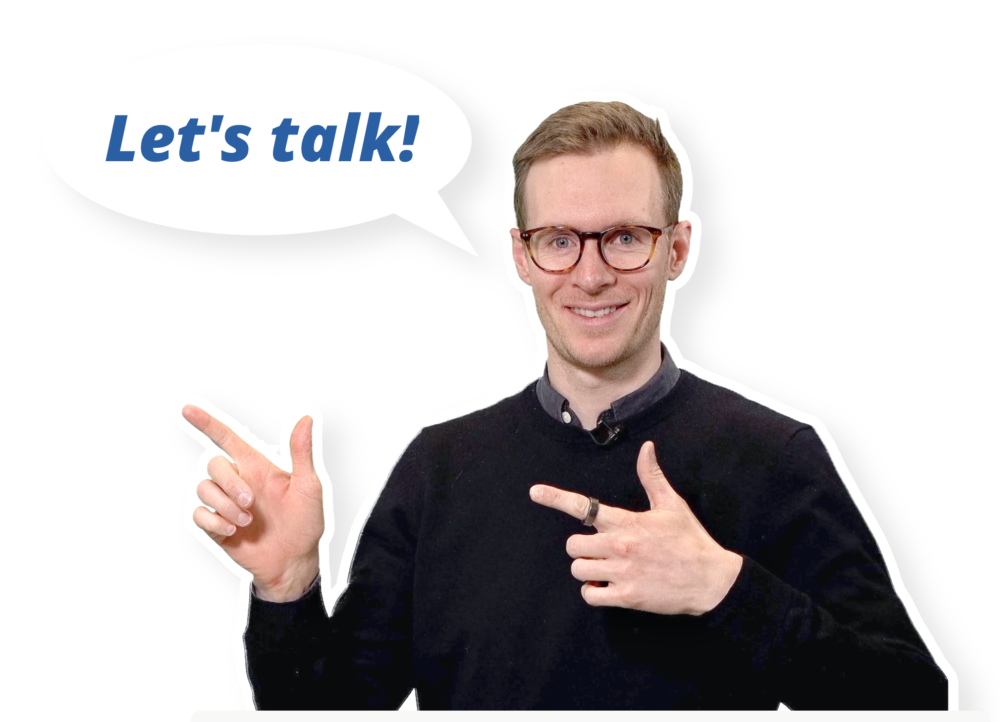 Person wearing glasses and a black sweater, pointing with both hands, speech bubble saying "Let's talk!" on a white background.
