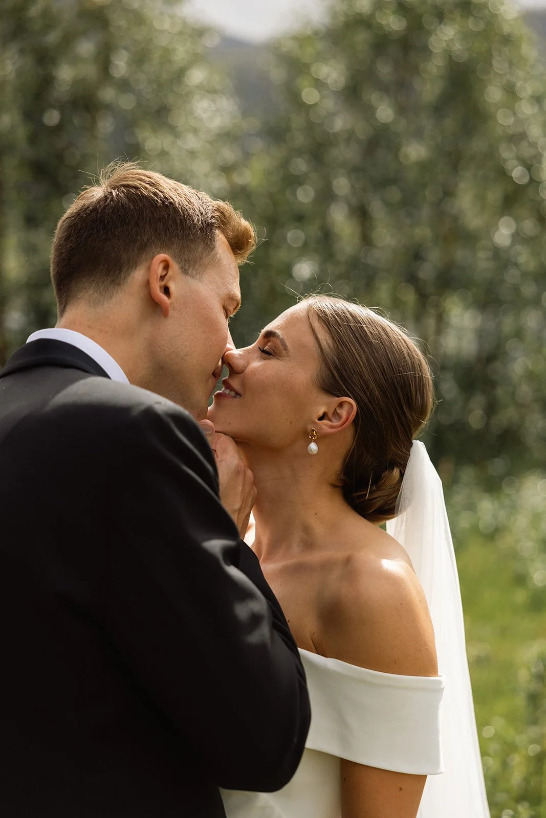 Nittelig bilde av et brudepar som kysser, med natur bakgrunn