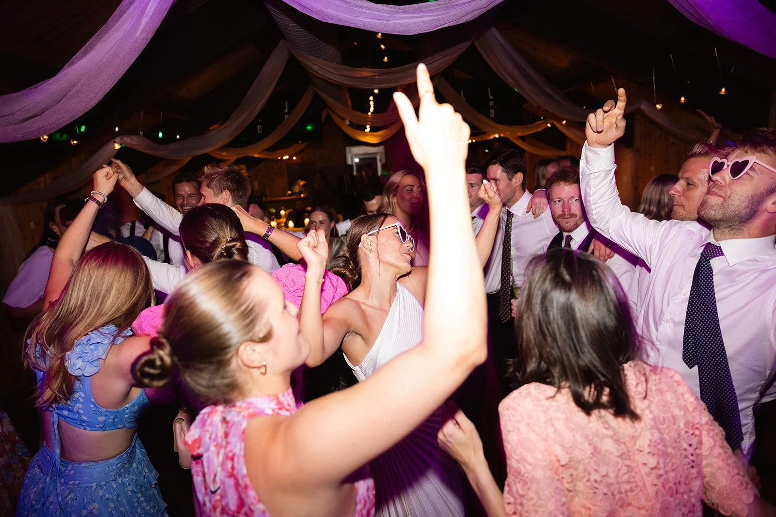 Mennesker danser og har det gøy på en fest med dekorative stoffbånd i taket.