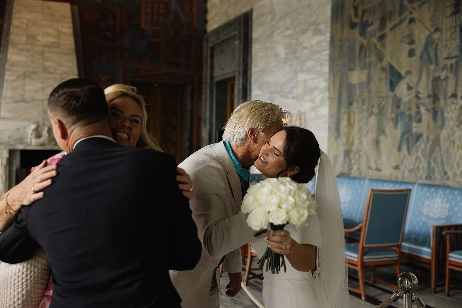 En glad brud og en eldre mann klemmer, mens en kvinne og en mann har en annet kyss på en annen side av bildet.