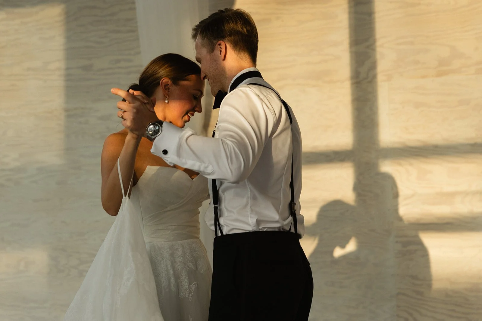 Et par danser i bryllupsklær, de er tett inntil hverandre med pannen mot pannen, på et dansegulv.